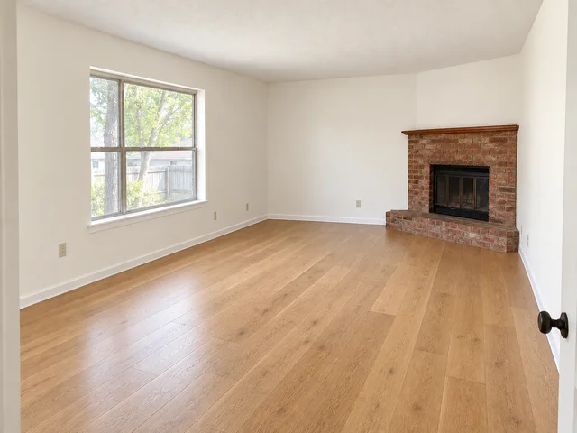The same living room with warm white walls, clean trim and wood flooring.